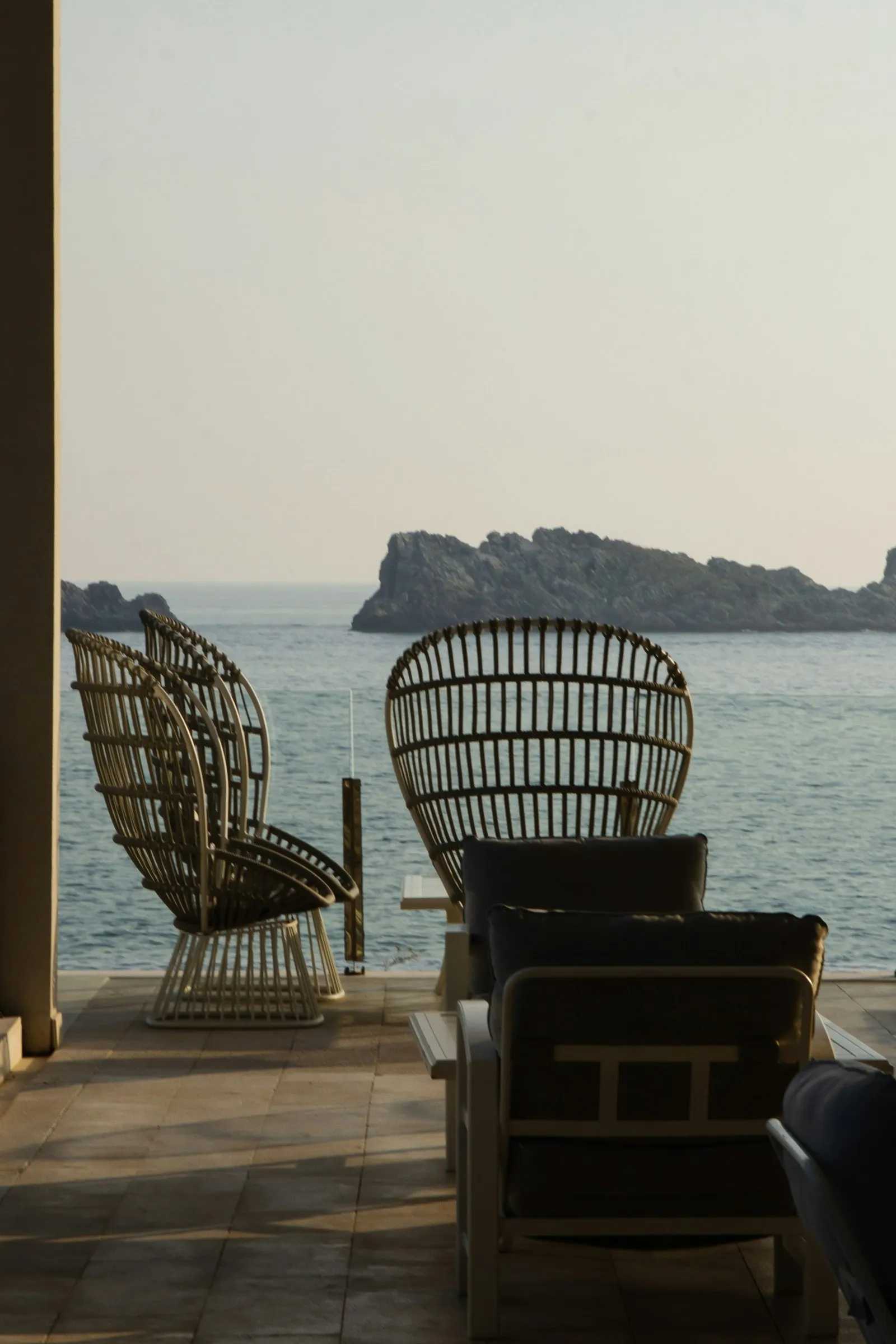 Due poltrone di vimini in terrazza, davanti al mare e a un isolotto